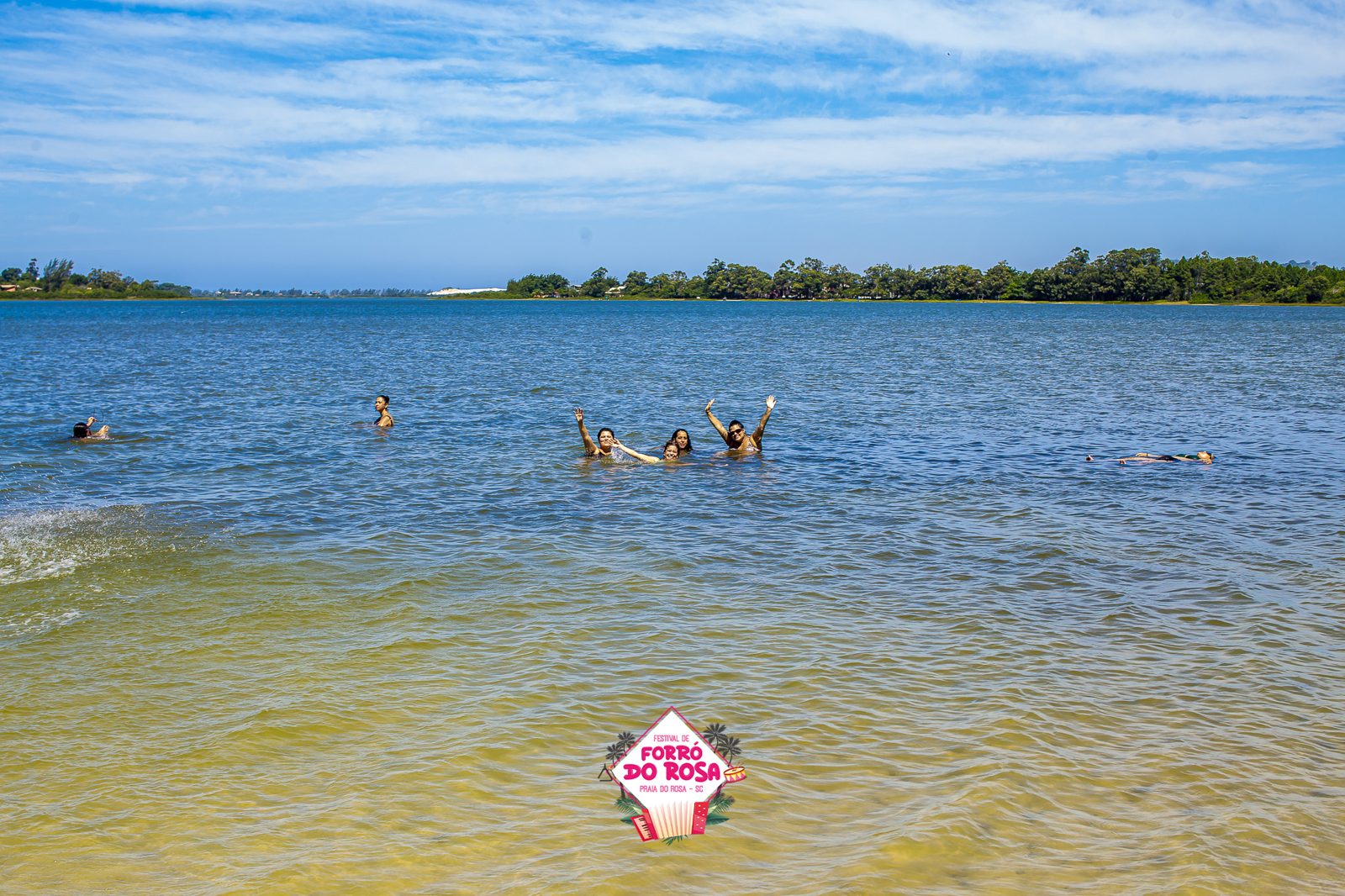 Lagoa da Praia do Rosa com pessoas nadando e morros verdes ao fundo